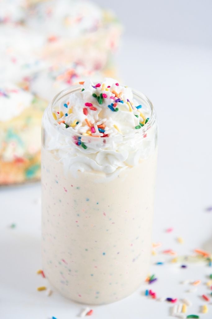 a finished birthday cake milkshake with sprinkles around it