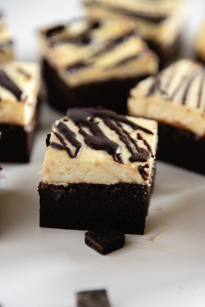 a cheesecake brownie with a chocolate chunk in front of it 