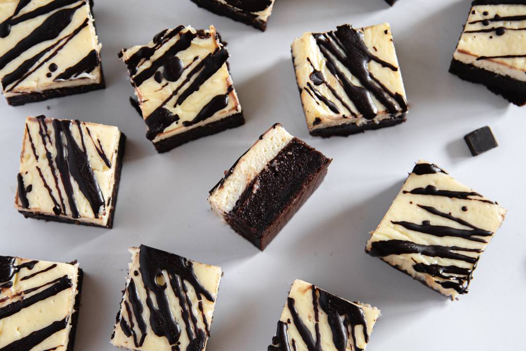 cheesecake brownies set out on a table, one of them flipped over on it's side 