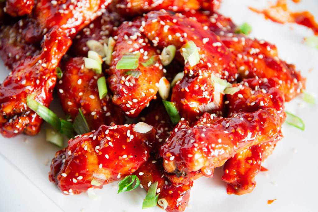 a pile of chicken wings with green onions on top 