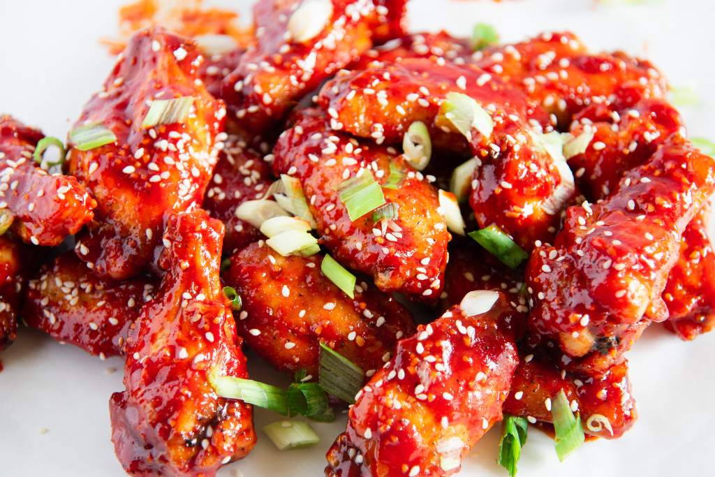 chicken wings piled up on top of each other, with green onions sprinkled on top