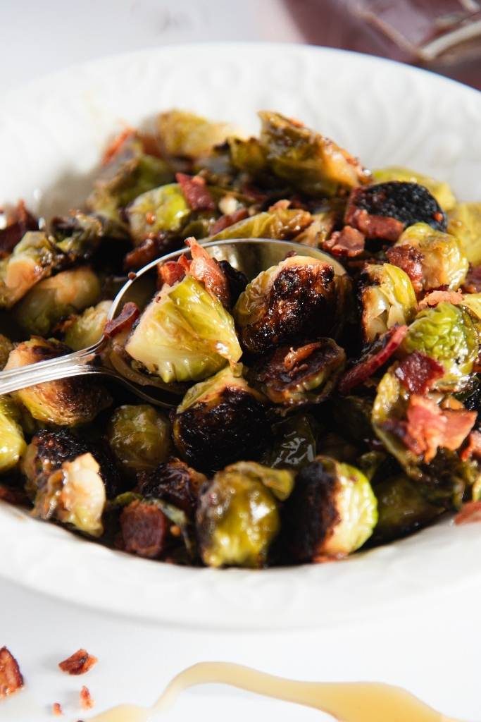 a spoon of brussels sprouts resting on a dish of brussels sprouts