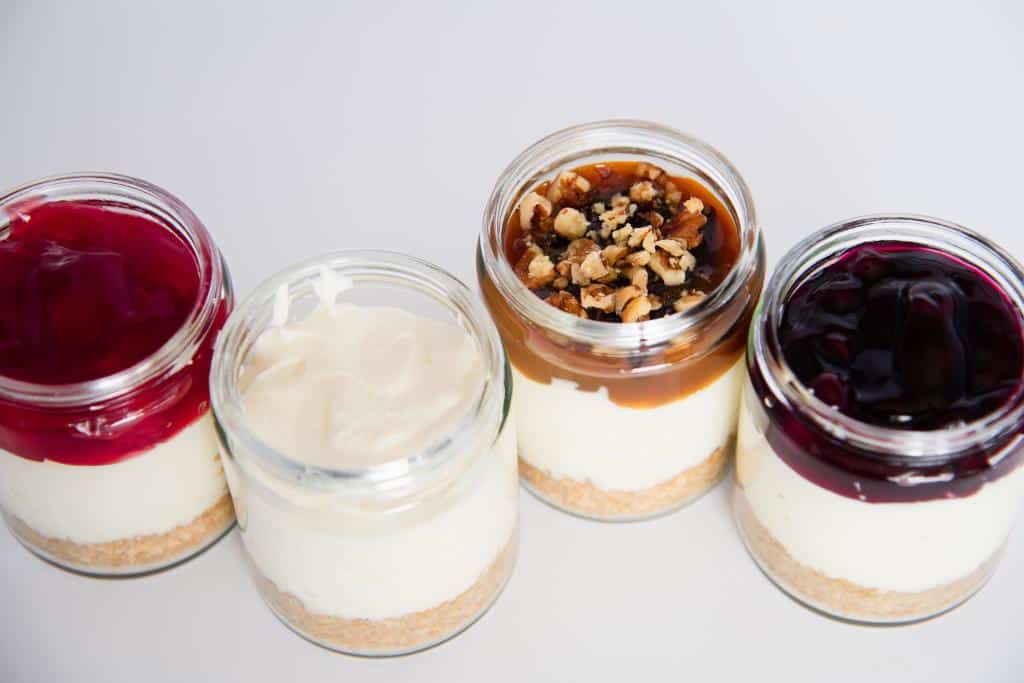 an overhead shot of four jars of cheesecake with different toppings