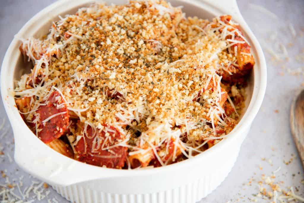 a dish of pizza pasta with a wooden spoon next to it 