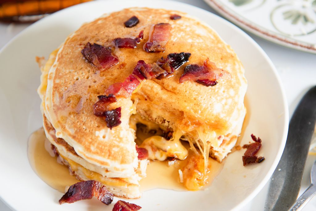 a plate of pancakes with bite cut out of them and syrup on top