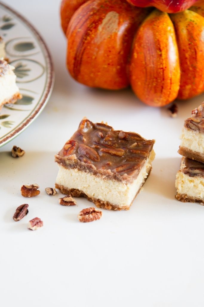 a pecan pie cheesecake bar in front of a pumpkin decoration