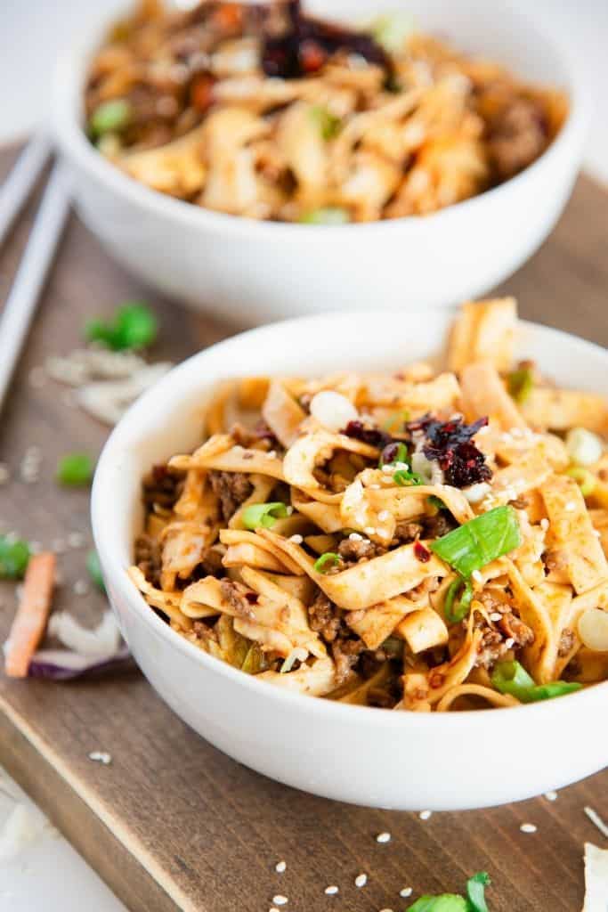 a bowl spicy noodles, with another bowl behind it