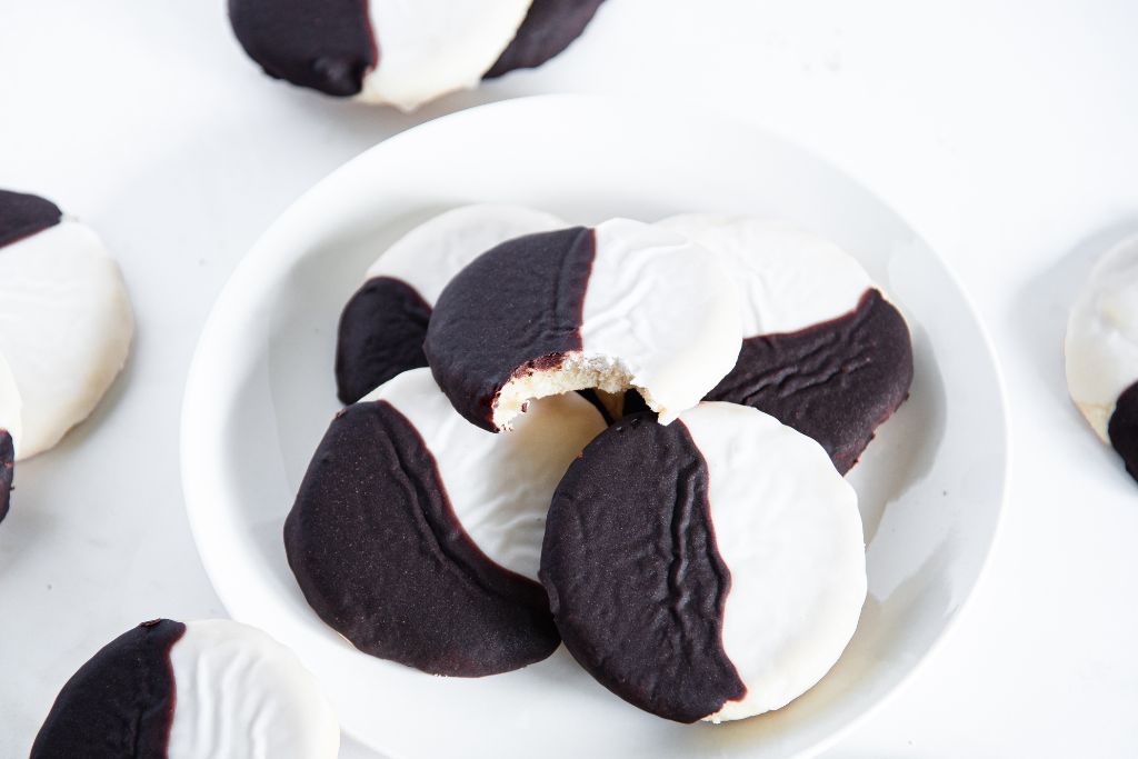 a plate of cookies, the cookie on top as a bite taken out of it 