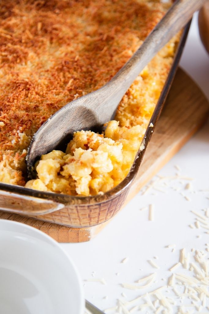 a wooden serving spoon stuck in a pan of mac and cheese