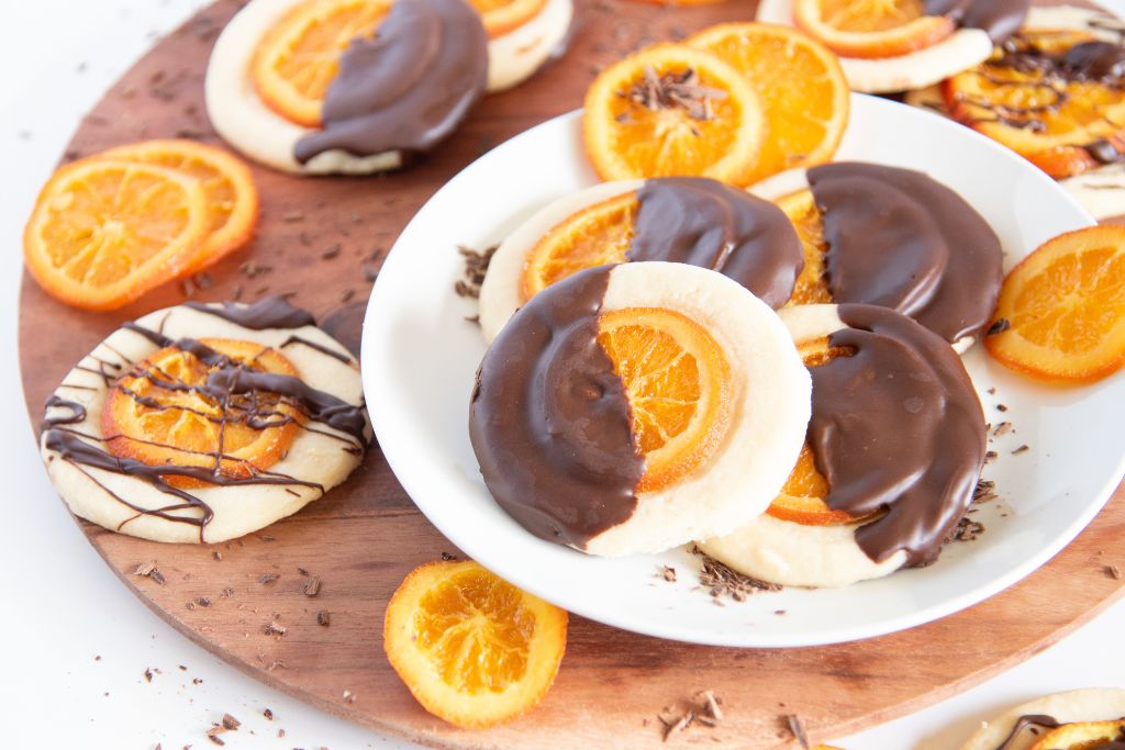 a plate of shortbread cookies, there are more cookies and candied orange slices behind them 