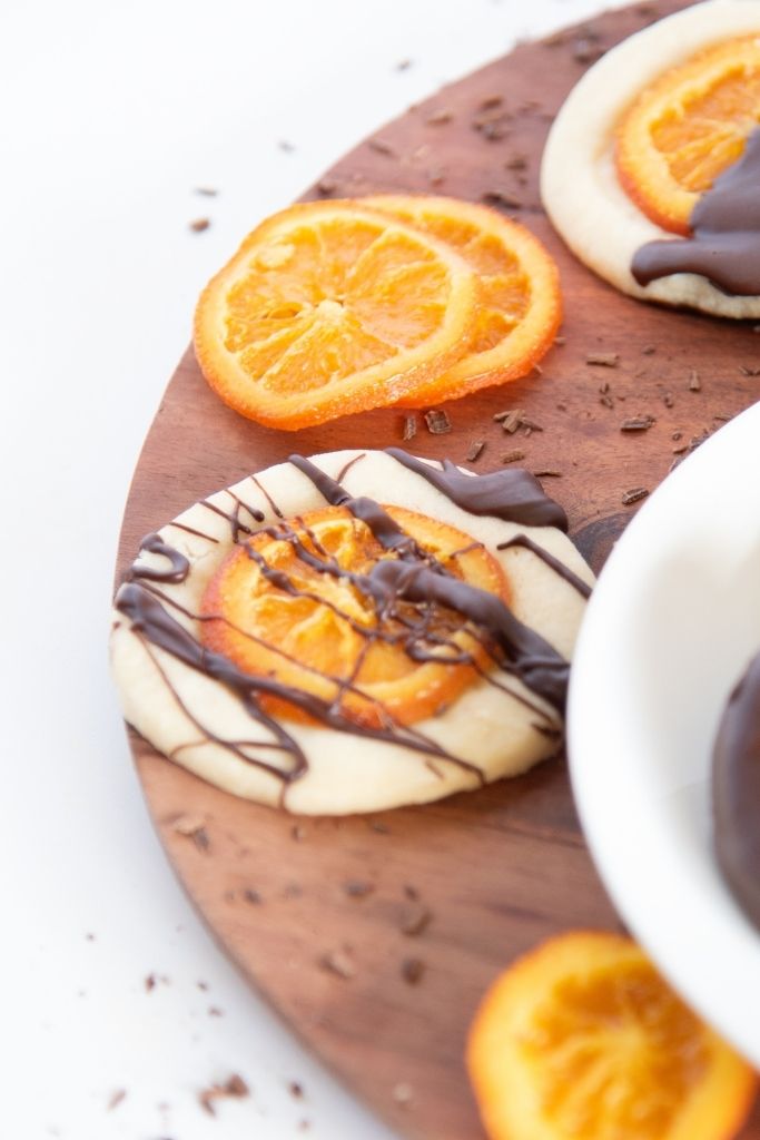 a close up of a candied orange shortbread cookie with chocolate drizzled on top 