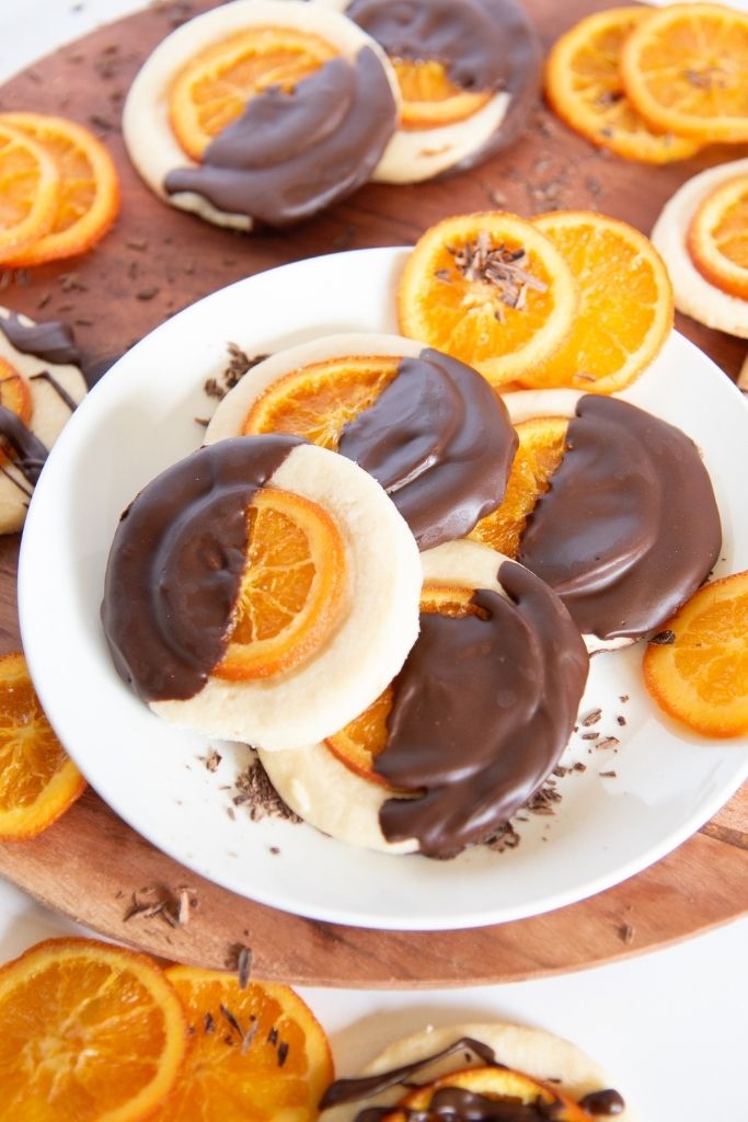 a plate of candied orange shortbread cookies, there are more cookies and candied orange slices behind 