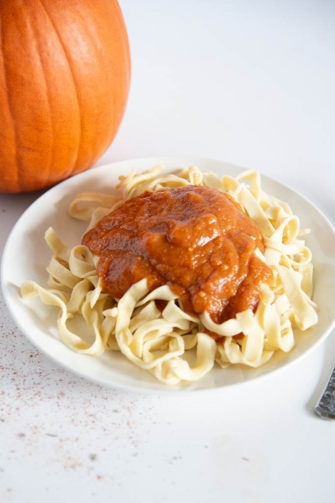 a plate of noodles with pumpkin sauce on top