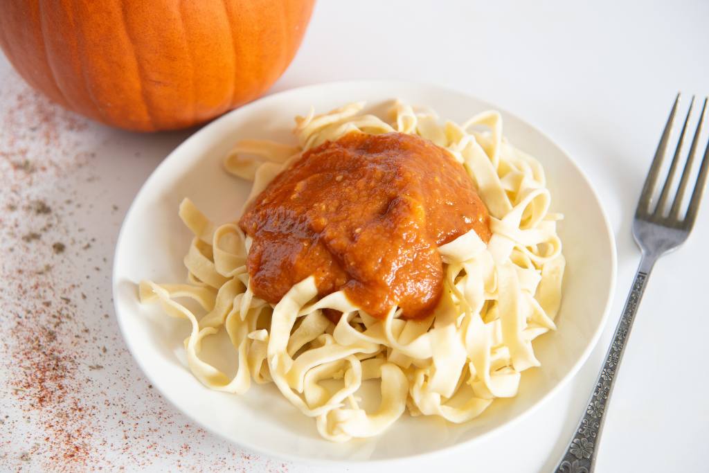 a plate of noodles with pumpkin pasta sauce on top