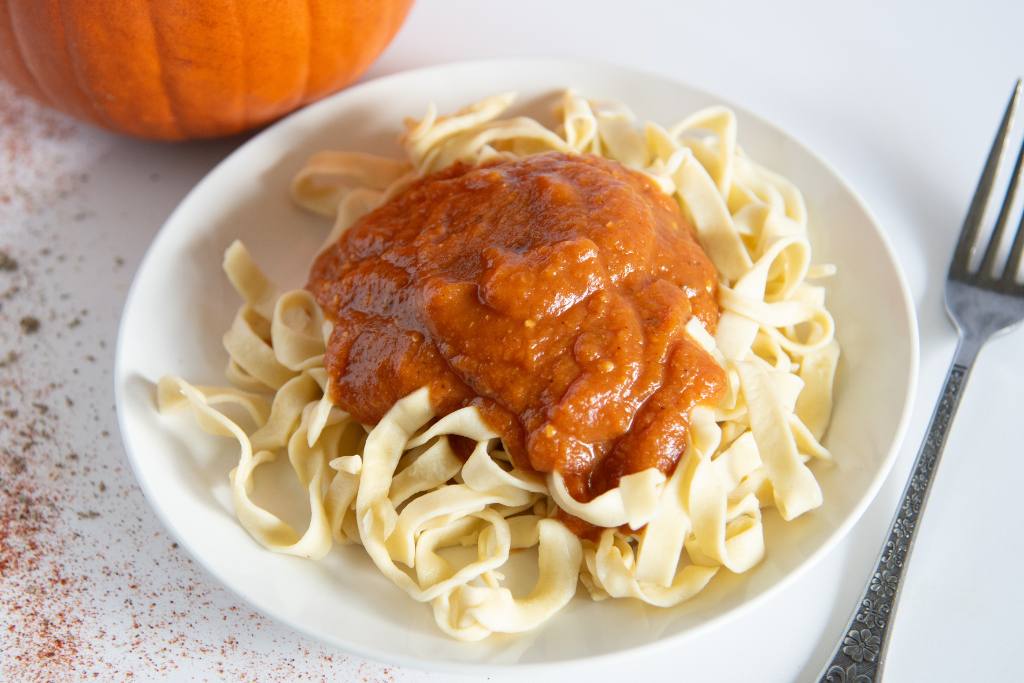 a plate of noodles with sauce on top, there is also a fork next to the plate