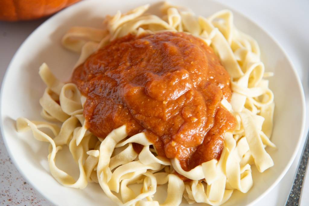 a close up of a plate of noodles with pumpkin sauce on top