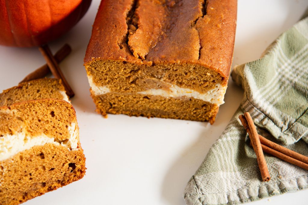 a loaf of bread with some bread slices, and cinnamon sticks next to it 