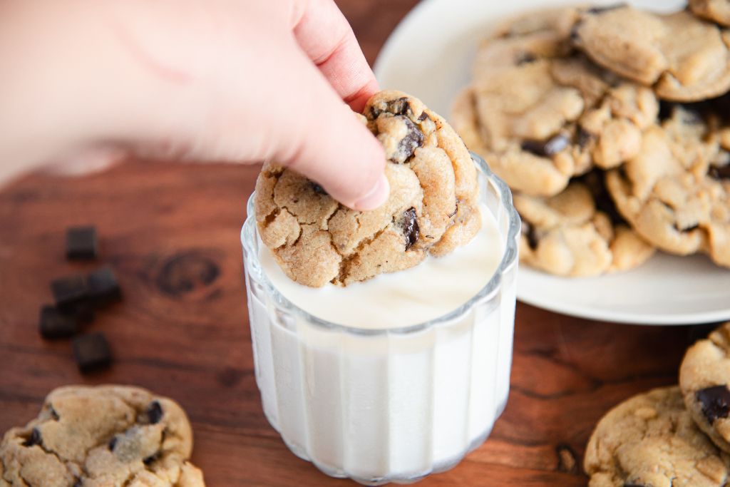 a cookie being dunked into a glass of milk