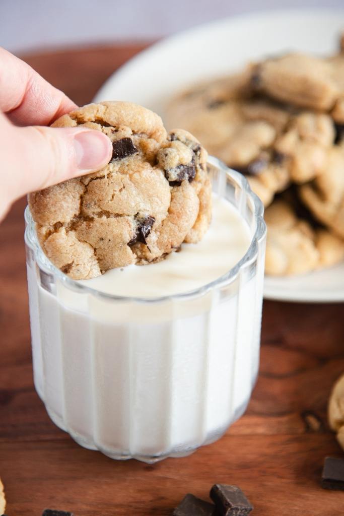 someone dunking a cookie into a glass of milk 