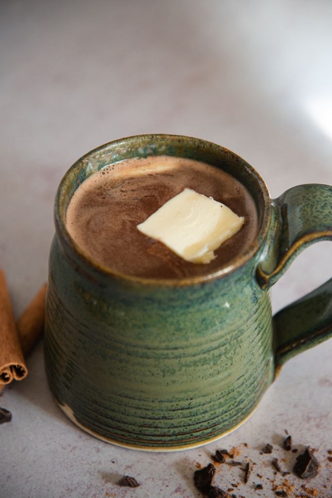 a cup of buttered rum hot chocolate with a pat of butter in it 