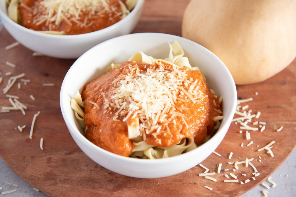 a bowl of noodles with sauce on top, there is another bowl of noodles behind it 