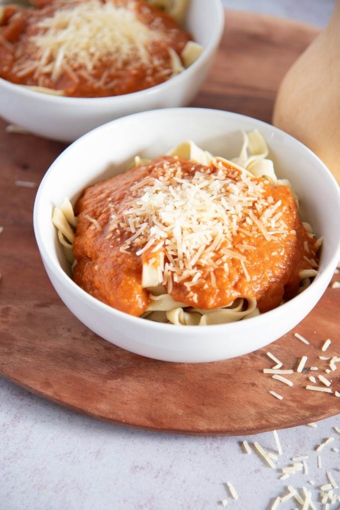 a bowl of noodles with sauce on top, there is another bowl behind it 