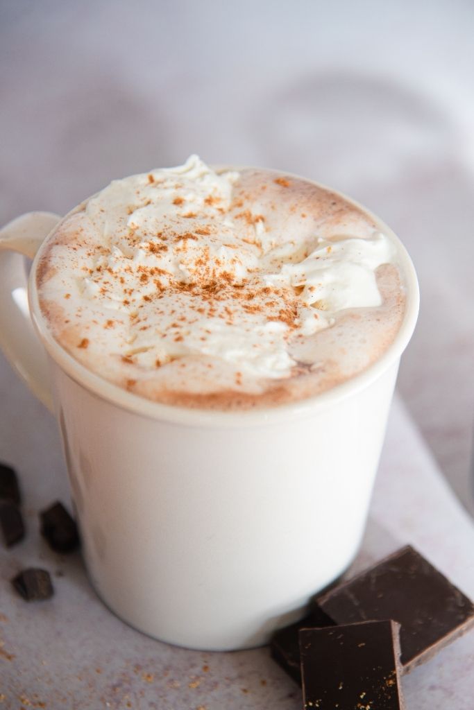 a cup of hot chocolate with pieces of chocolate next to it 