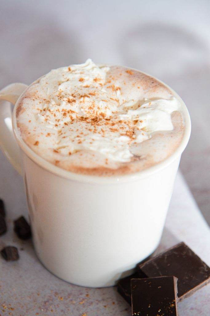 a cup of gingerbread hot chocolate with pieces of chocolate next to it