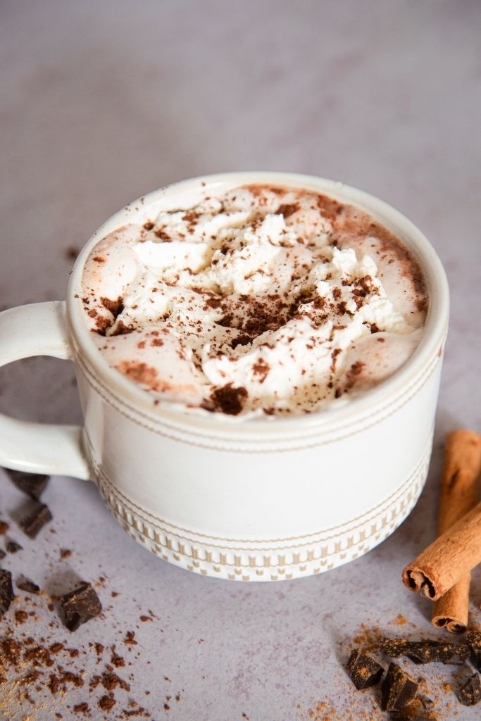 a close up of a mug of chai not chocolate with whipped cream on top