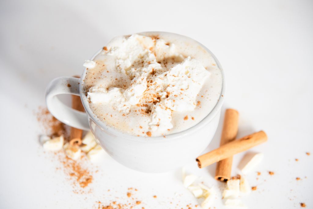 a finished latte with chocolate and cinnamon sticks next to it 