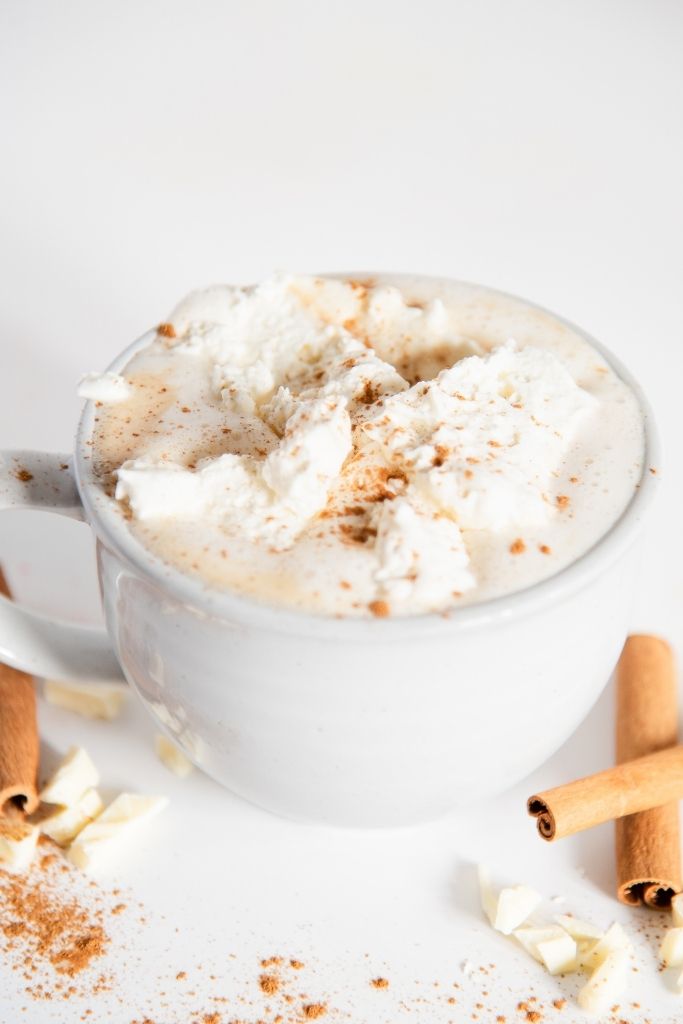 a cinnabon latte with cinnamon sticks next to it 