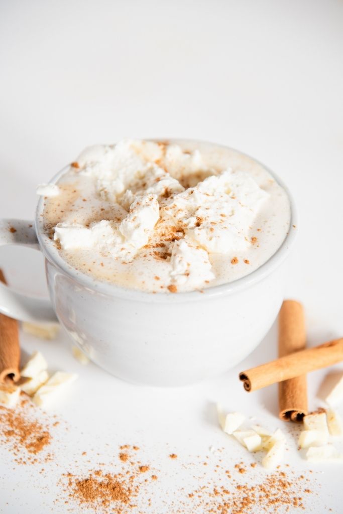 a cinnabon latte with white chocolate and cinnamon sticks next to it 