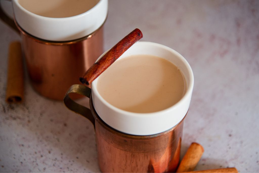 a bourbon chai nightcap with a a cinnamon stick resting on the edge of the cup