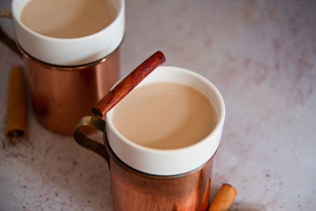 two bourbon chai nightcaps, one has a cinnamon stick resting on the edge of it