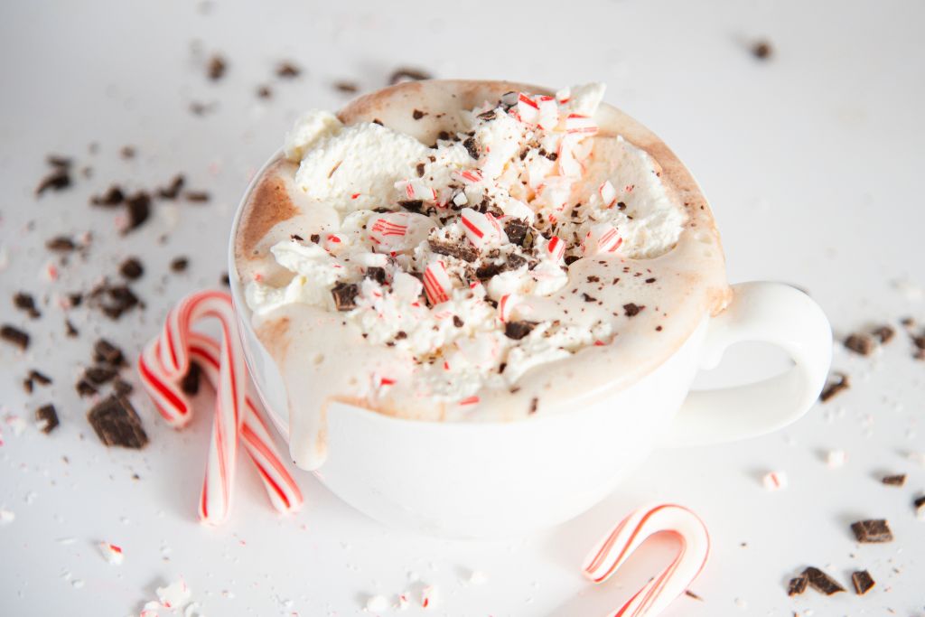 a cup of hot chocolate topped with whipped cream, of the whipped cream as started to melt and spill down the side of the cup