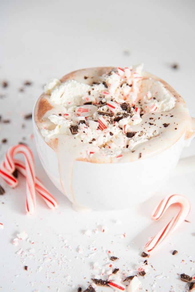 a cup of peppermint hot chocolate with melted whipped cream spilled down the side of the cup