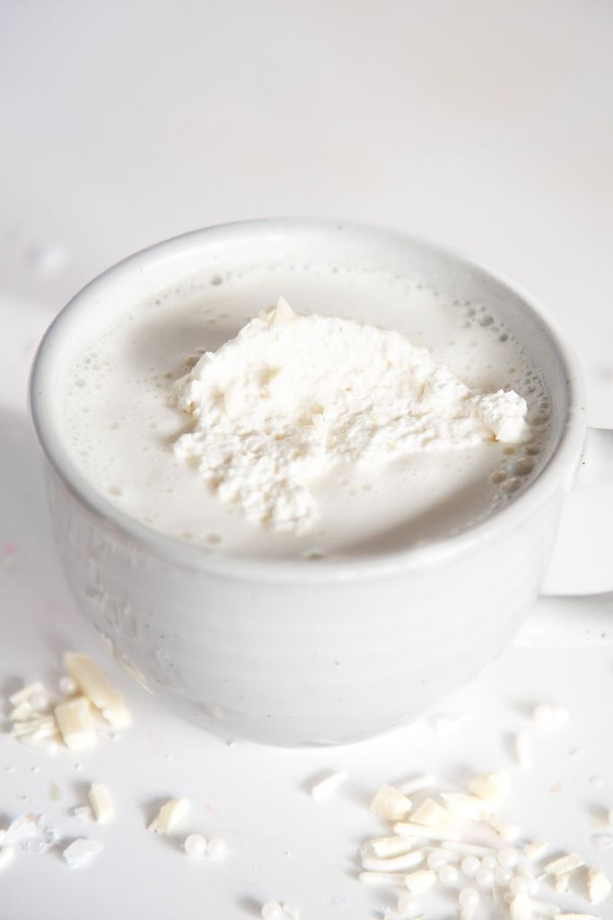 a cup of hot chocolate with chopped white chocolate next to it 