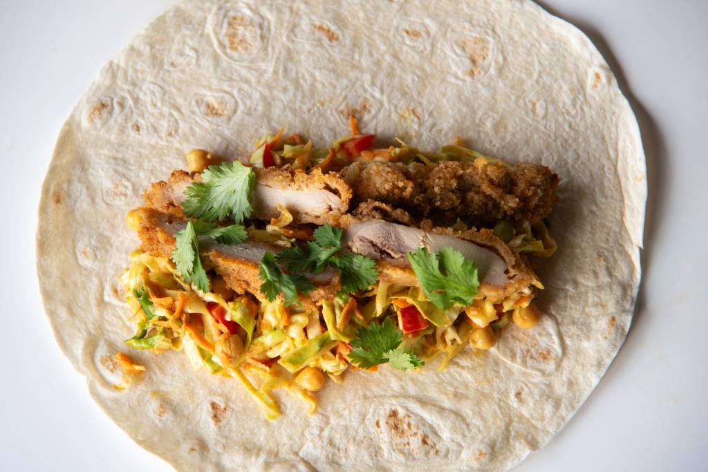 a tortilla with wrap filling on it, that hasn't been rolled up yet.