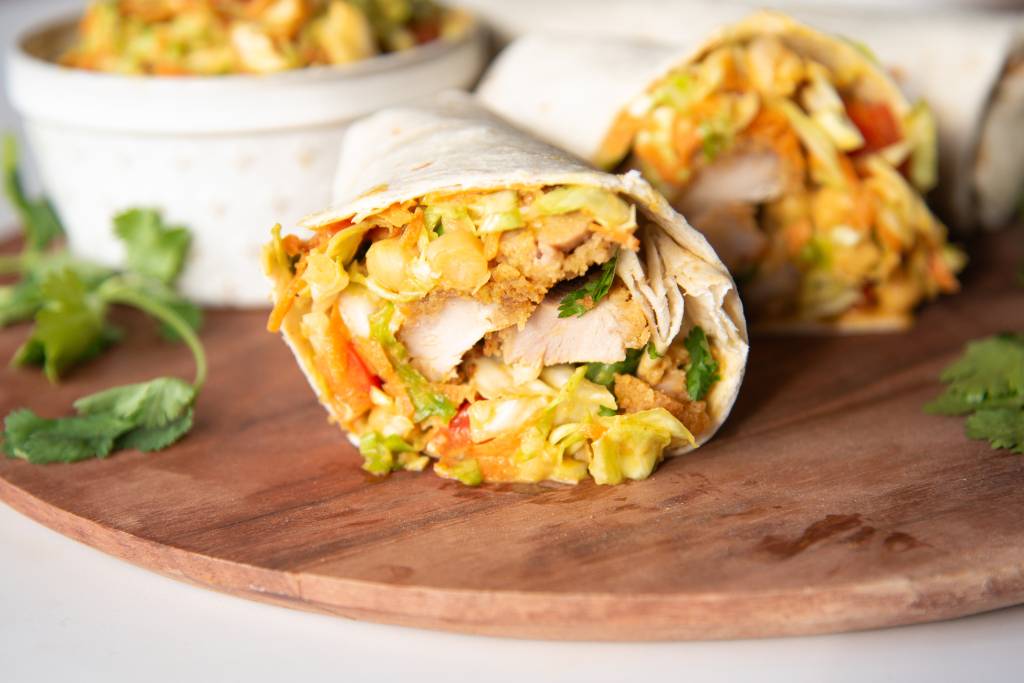 a close up of a wrap that has been cut in half, you can see the other half of it and a dish in the background