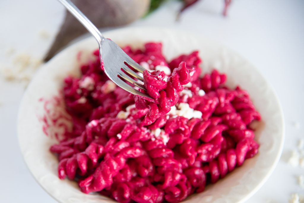 a fork full of pasta being held over a bowl of pasta 