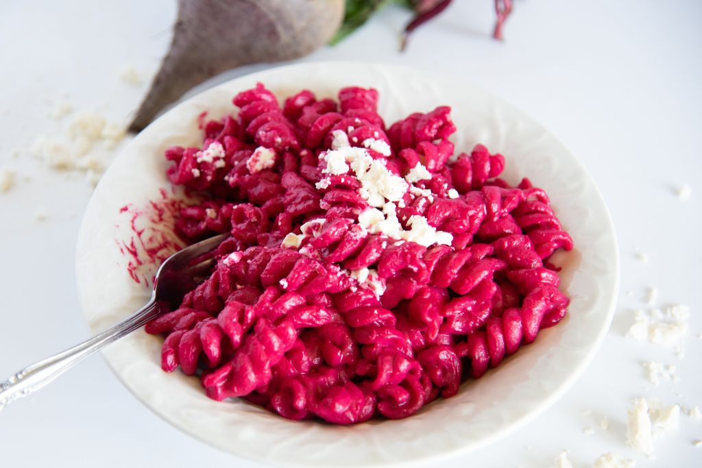 a bowl full of pasta covered in sauce, there is also a fork stuck into the pasta 