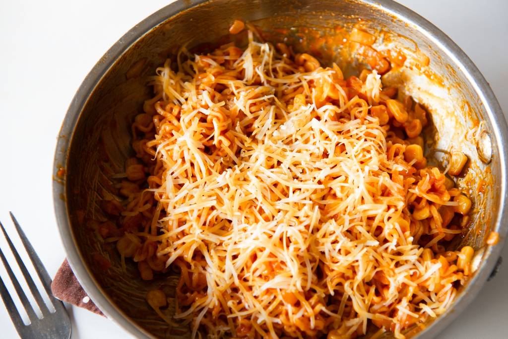 a pan noodles with cheese on top, there is also a fork next to the pan