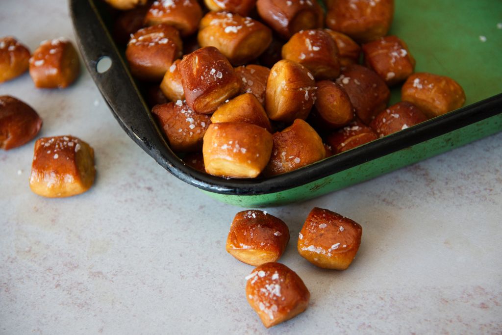 a green dish of pretzel bites, there also some pretzel bites on the table next to the dish