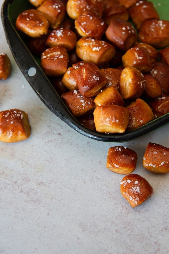 a green dish full of pretzel bites, there also some on the table next to the dish