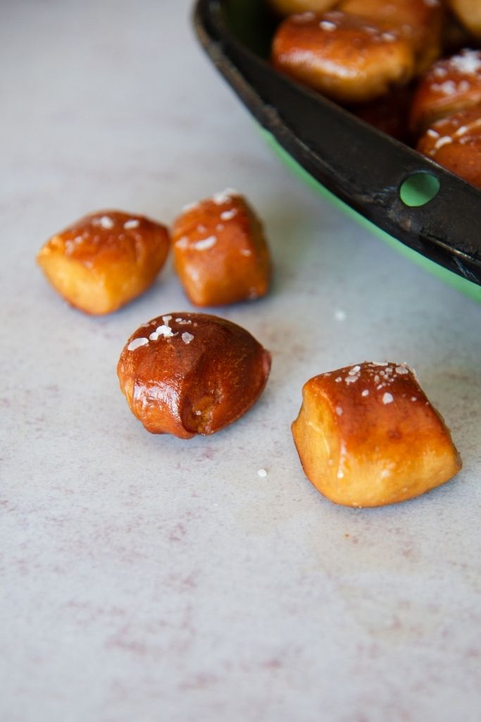 a close up of pretzel bites on a table, you can see part of green dish behind them