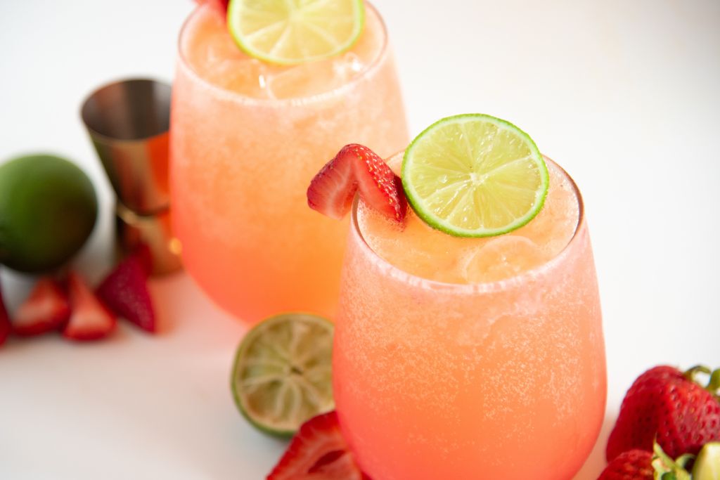 two mocktails with strawberries and limes around them