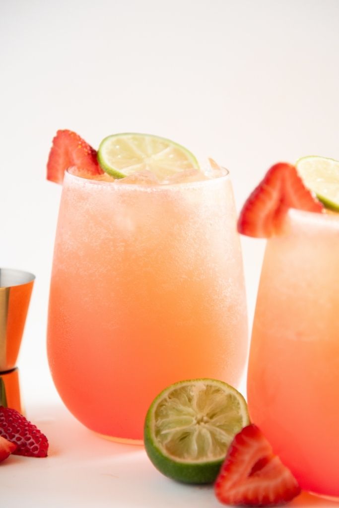 a mocktail with a measuring cup next to it, and a half of a lime