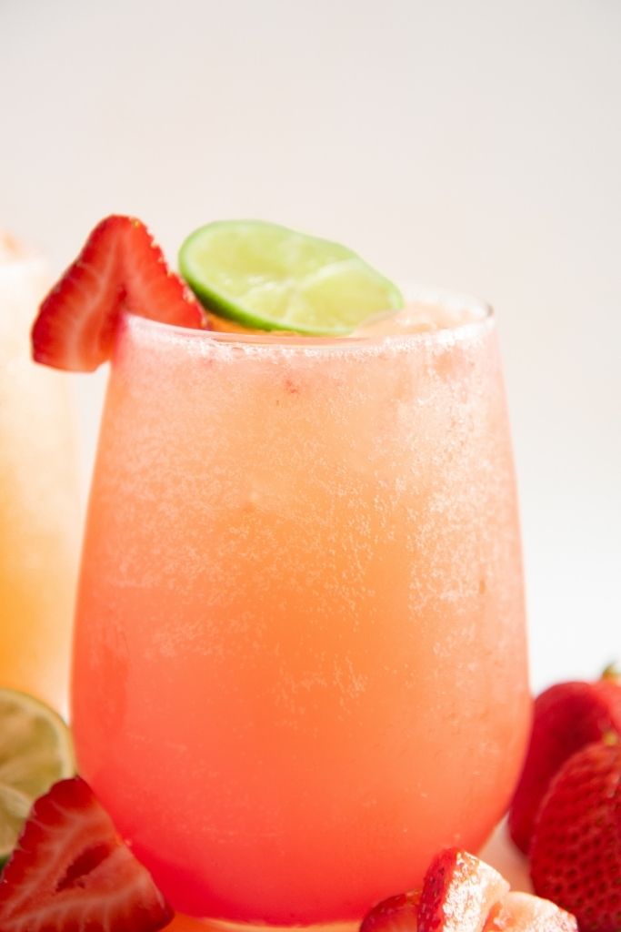 a close up of a mocktail, you can see some strawberries and part of a lime next to it