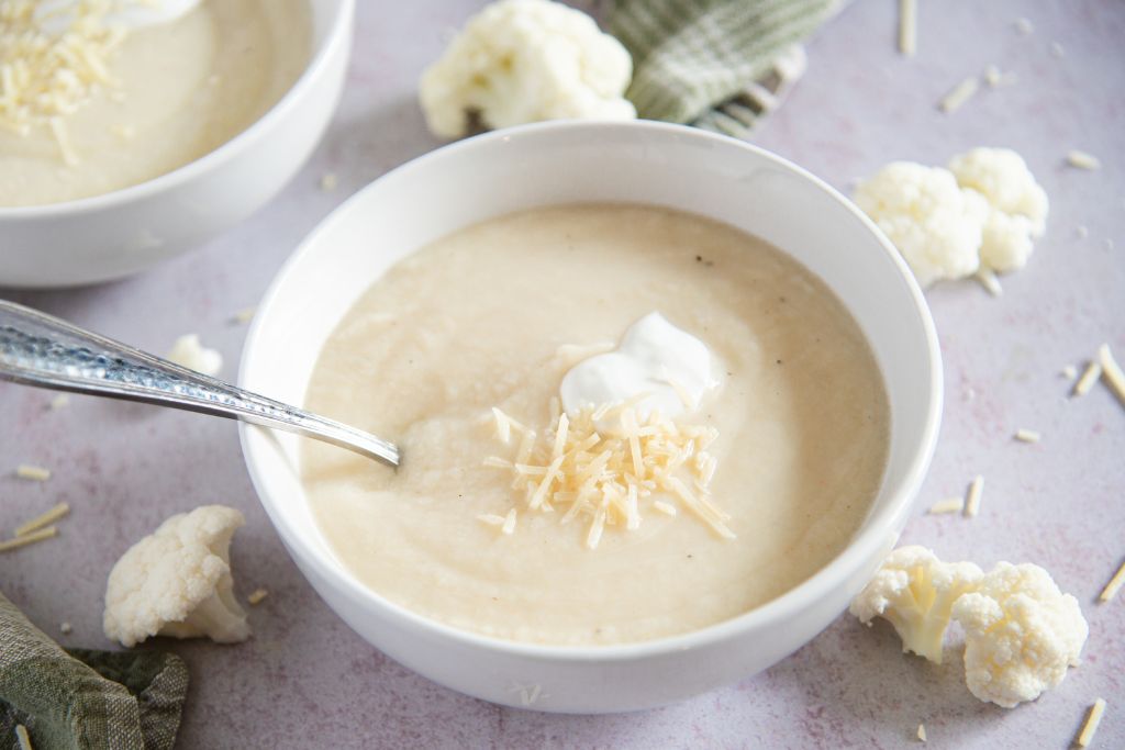 a bowl of soup with a spoon in it you can see part of another bowl of soup behind it 