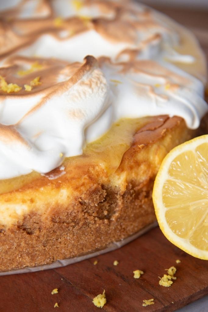 a close up of an uncut cheesecake with half a lemon next to it